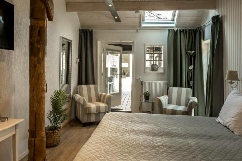 een slaapkamer met een bed en 2 stoelen en een raam bij Hotel B&B Hoeve de Vredenhof in Zuidlaren