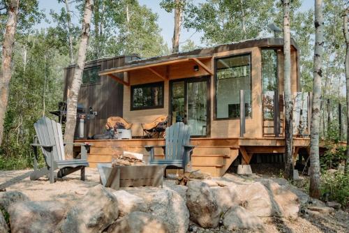 uma pequena casa na floresta com duas cadeiras em Refuge Bay's Aqua Tiny Home - Luxury Off Grid Escape 
