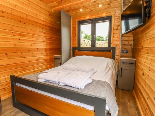 ein Schlafzimmer mit einem Bett in einem Blockhaus in der Unterkunft Oak Lodge At Bridge Lake Farm & Fishery in Banbury