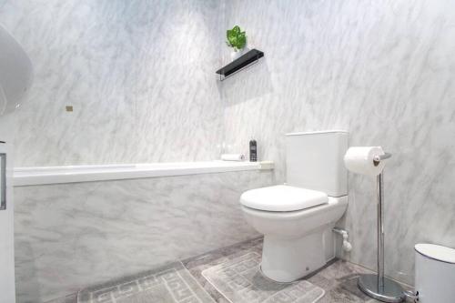 a white bathroom with a toilet and a plant on the wall at The Ojay's - Gustina Apartment in Aberdeen
