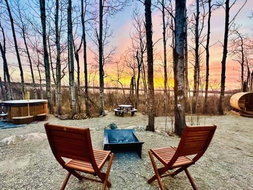 two chairs and a fire pit in the woods at Refuge Bay's Aqua Tiny Home - Luxury Off Grid Escape 