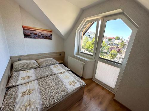 een slaapkamer met een bed en een groot raam bij Willa CETNIEWSKA in Władysławowo