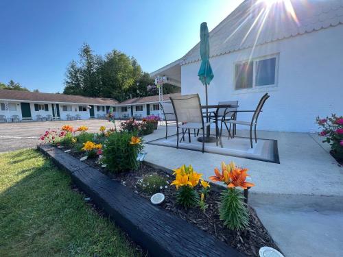 a patio with a table and chairs and flowers at Cedars Motel in Saint Ignace