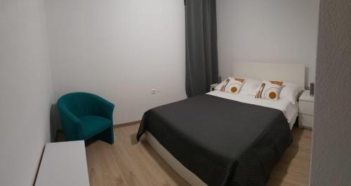 a bedroom with a bed and a green chair at Apartman Skoko in Sevid