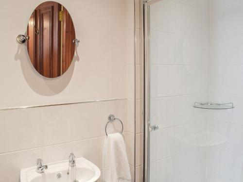 a bathroom with a shower and a sink and a mirror at Sorbie Villa in Stevenston