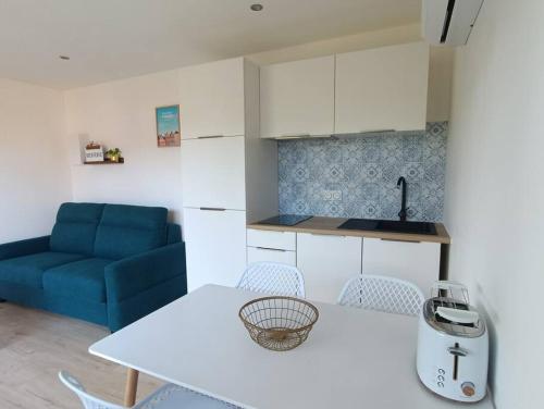 a kitchen with a white table and a blue couch at Loft privatif TYGLAZ - Golfe du Morbihan in Sarzeau