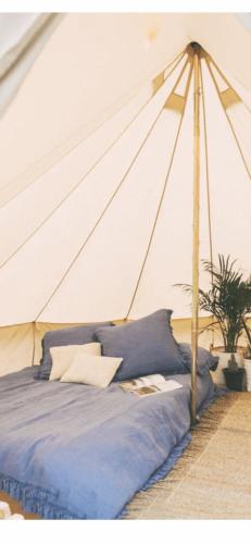 a bed in a tent with blue sheets and pillows at Dadford campsite in Silverstone