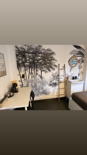 Zimmer mit einem Schreibtisch und Palmen an der Wand in der Unterkunft La villa Bastogne chambre d'hôtes 2 in Bastogne