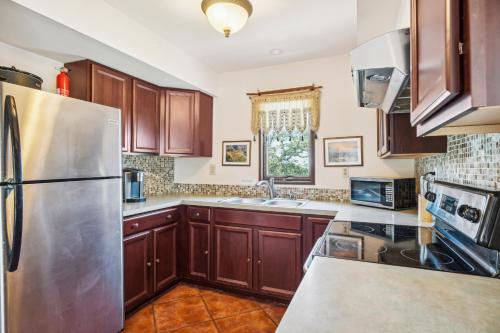 a kitchen with wooden cabinets and a stainless steel refrigerator at Pipe Creek Escape with Screened-In Porch and Hot Tub! in Pipe Creek