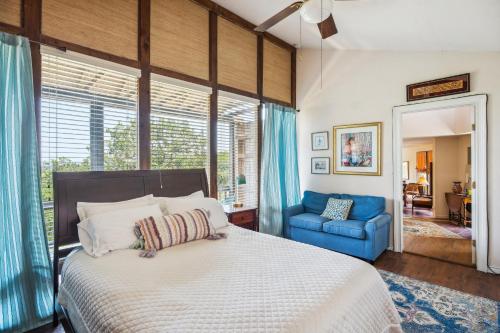 1 dormitorio con 1 cama grande y 1 silla azul en Pipe Creek Escape with Screened-In Porch and Hot Tub!, en Pipe Creek