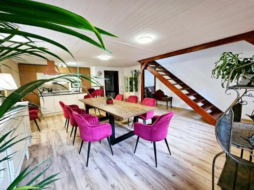 uma sala de jantar com uma mesa de madeira e cadeiras cor-de-rosa em UV Apartmány em Banská Štiavnica
