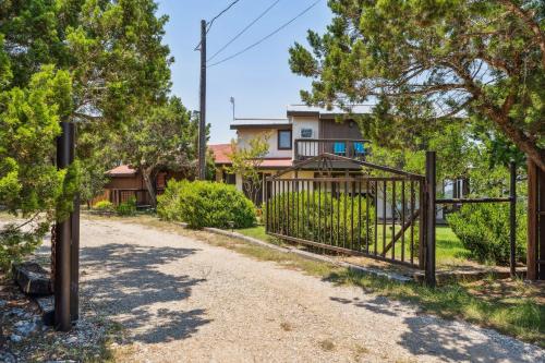 a gate in front of a house with trees at Pipe Creek Escape with Screened-In Porch and Hot Tub! in Pipe Creek