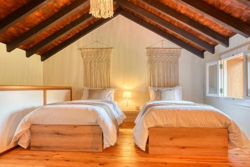 two beds in a bedroom with wooden floors at Chalet da Nogueira, a Home in Madeira in Ponta do Sol