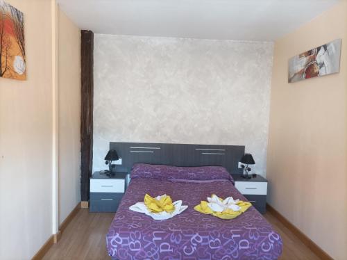 Un dormitorio con una cama púrpura con dos flores. en El Loft de Cris, en Béjar