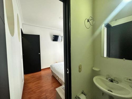 ein Bad mit einem Waschbecken und ein Bett in einem Zimmer in der Unterkunft Hotel Artistico in Bogotá