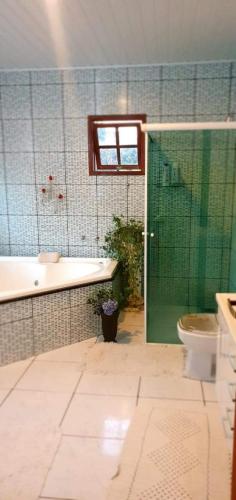 a bathroom with a tub and a toilet and a glass door at Pousada Remanso do Rio Preto in Visconde De Maua