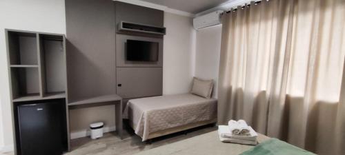 a small room with a bed and a television at Pousada Kaki Haus in Pomerode