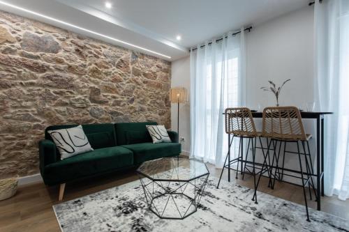 a living room with a green couch and a stone wall at Zalaeta Playa Apartments in A Coruña