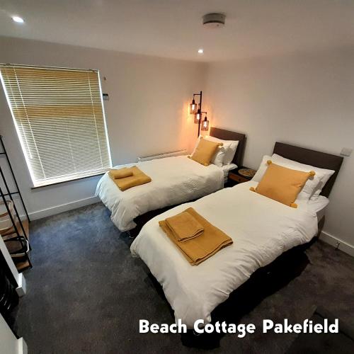 a bedroom with two beds with towels on them at Beach Cottage Pakefield- Newly Fully Renovated House in Pakefield