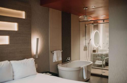 um quarto de hotel com uma cama e uma banheira em CityFlatsHotel - Grand Rapids, Ascend Hotel Collection em Grand Rapids
