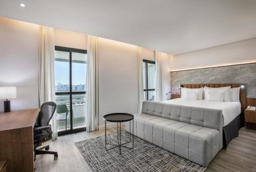 een hotelkamer met een groot bed en een bureau bij Meliá Jardim Europa in Sao Paulo