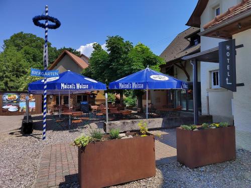 a restaurant with blue umbrellas in front of a building at Hotel "Cafe Verkehrt" - Wellcome Motorbiker, Berufsleute und Reisende im Schwarzwald in Oberhof