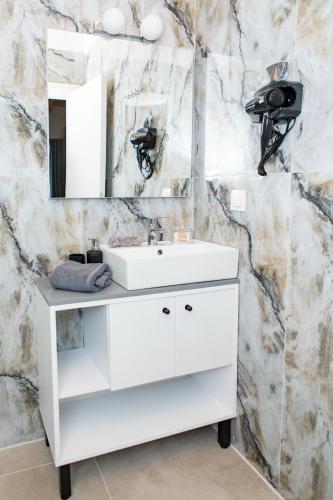 a bathroom with a white sink and a mirror at Four Princess in Agia Paraskevi