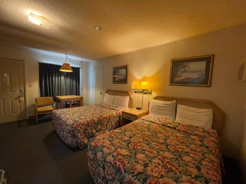 una habitación de hotel con 2 camas y una silla en Twin Pine Motel, en Tipton