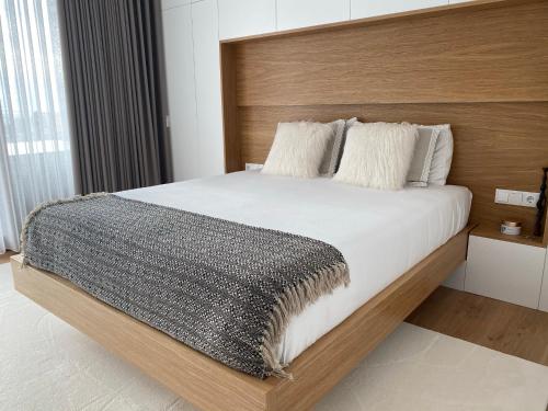 Schlafzimmer mit einem großen Bett mit einem Kopfteil aus Holz in der Unterkunft PEARL by Balgrid in Viana do Castelo
