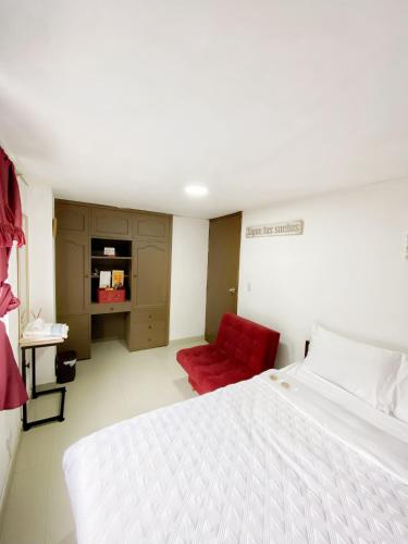 a bedroom with a white bed and a red chair at Royal Rooms in Bogotá
