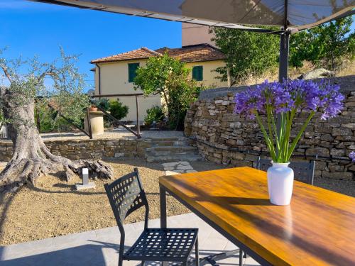 a wooden table with a vase of purple flowers on it at Casa Mara - Diano Serreta in Diano Marina