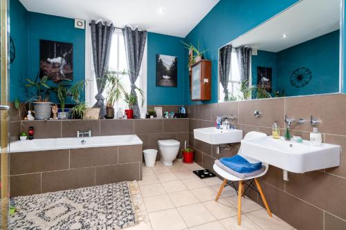 Baño con 2 lavabos y paredes azules en Master En - Suite Townhouse double with Garden & Hot Tub, en Londres