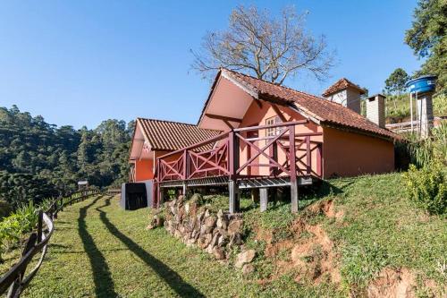 uma casa vermelha no topo de uma colina em Chales Fazenda Cantinho do Selado em Monte Verde