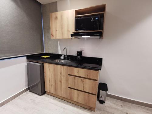 a small kitchen with a sink and a microwave at Eutopiq Hotel in Medellín