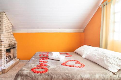 a bed with red flowers on it in a bedroom at Chales Fazenda Cantinho do Selado in Monte Verde