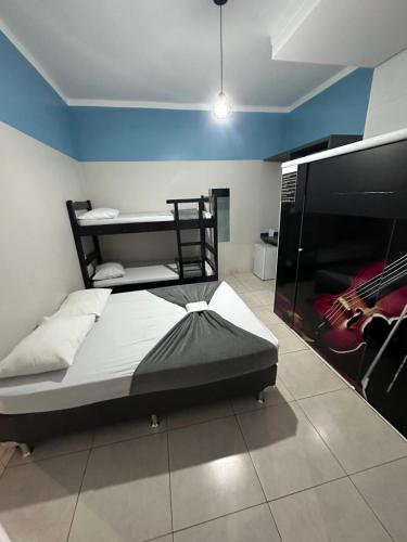 a bedroom with a bed with a guitar on the wall at Pousada Vitória Régia Olímpia in Olímpia