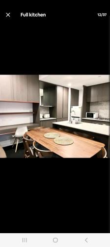 une grande cuisine avec une table et des chaises en bois dans l'établissement NESUTO DOCKLANDS, à Melbourne