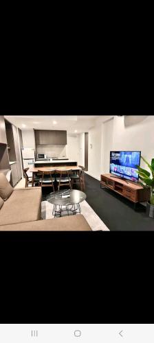 a living room with a table and a large screen tv at NESUTO DOCKLANDS in Melbourne