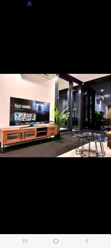sala de estar con TV, mesa y sillas en NESUTO DOCKLANDS en Melbourne