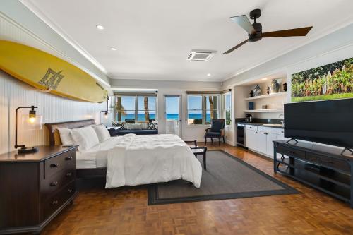 a bedroom with a bed and a flat screen tv at Classic 3br Oceanfront Cottage - Alekona Kauai in Koloa