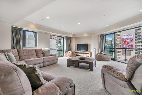 a large living room with couches and a tv at QV Stays Front Stage City Lights in Auckland