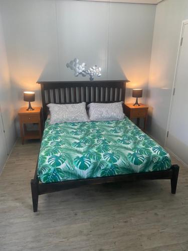 a bedroom with a bed with a green comforter at BEE LOCAL LABHOUSE in Fare