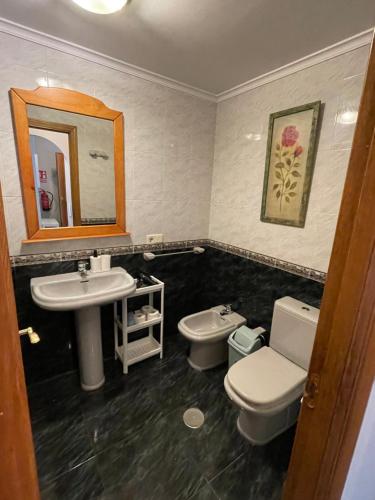 een badkamer met een wastafel, een toilet en een spiegel bij Viviendas Turísticas Los Cubos de Llanes 3 in Llanes