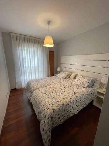 ein Schlafzimmer mit einem großen Bett mit einer weißen Tagesdecke in der Unterkunft Apartamentos Los Cubos de Llanes 3 in Llanes