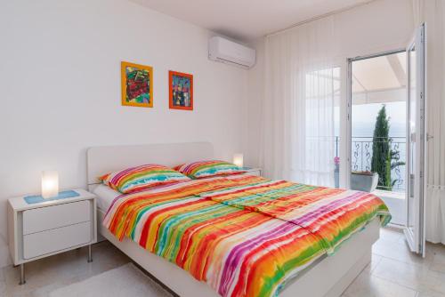 een witte slaapkamer met een groot bed en een kleurrijke deken bij Apartments by the sea Medveja, Opatija - 7720 in Lovran