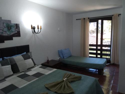 a bedroom with a bed and a chair and a window at Pousada Vênus in Monte Verde