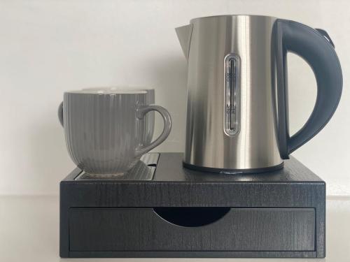a silver appliance sitting on a black stand with a cup at Westminster Guest House in Oxford