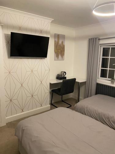 a hotel room with two beds and a desk and a television at Westminster Guest House in Oxford