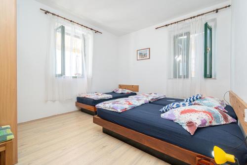 two beds in a room with white walls and windows at Seaside holiday house Preko, Ugljan - 21106 in Poljana