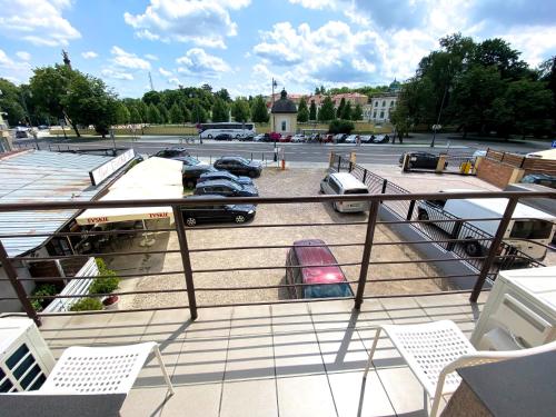 einen Balkon mit Stühlen und einen Parkplatz mit Autos in der Unterkunft Apartamenty Pałacowe in Białystok